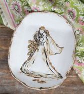 A hand-painted ceramic plate featuring a couple making a heartfelt wedding vow, with a bouquet of flowers in their hands. The plate has a rustic finish and floral pattern in the background.